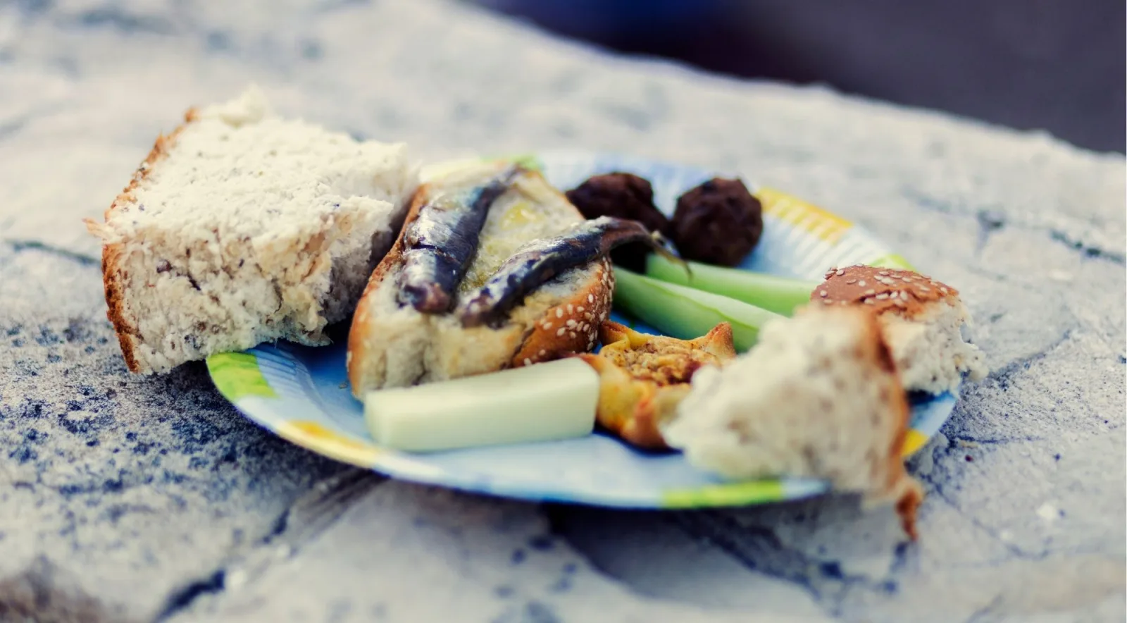 A plate of Cretan mezze — bread, cured anchovies, olives, cucumber and a small pie