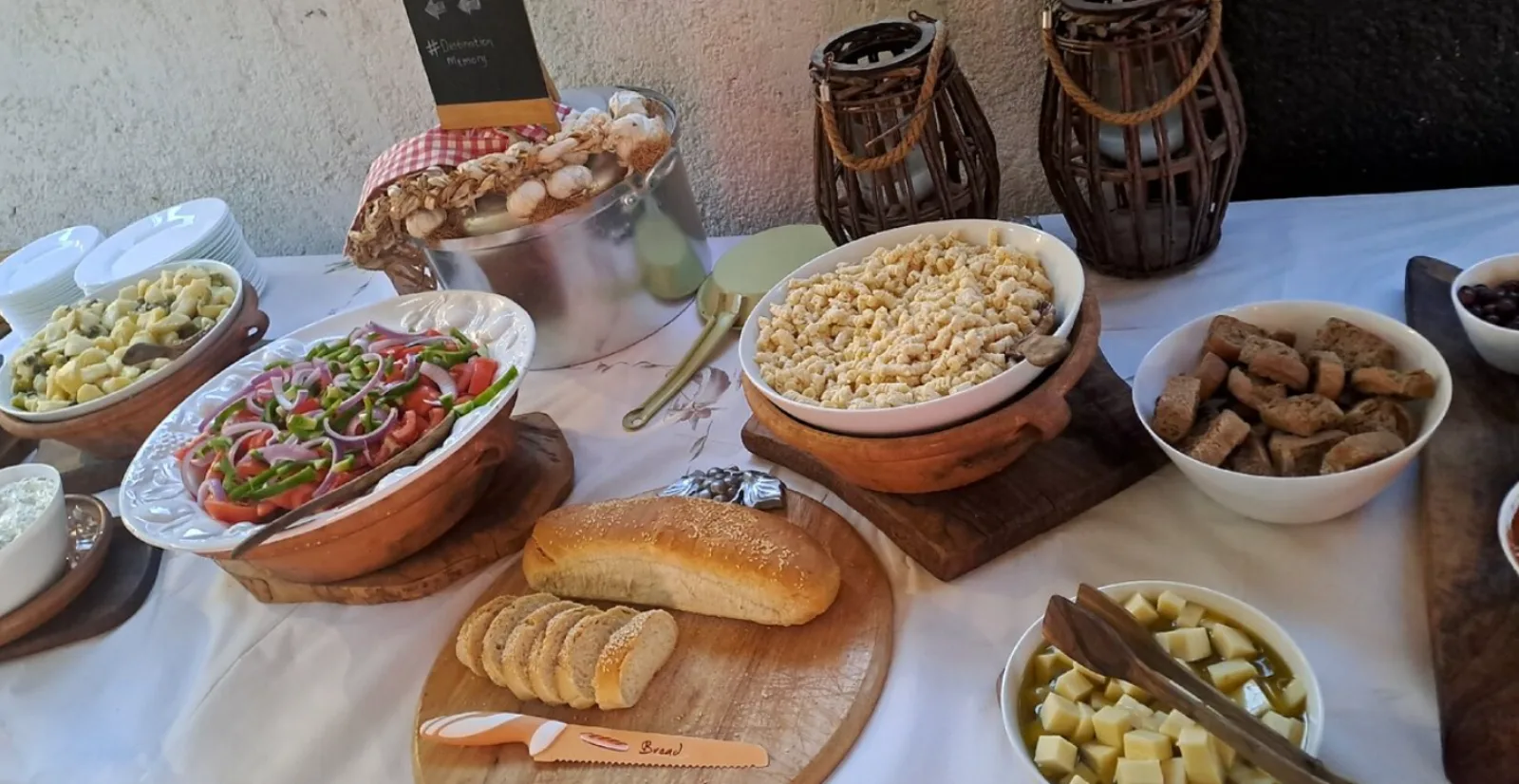 A long table laid with bowls of salad, dips, olives and bread in traditional Cretan pottery