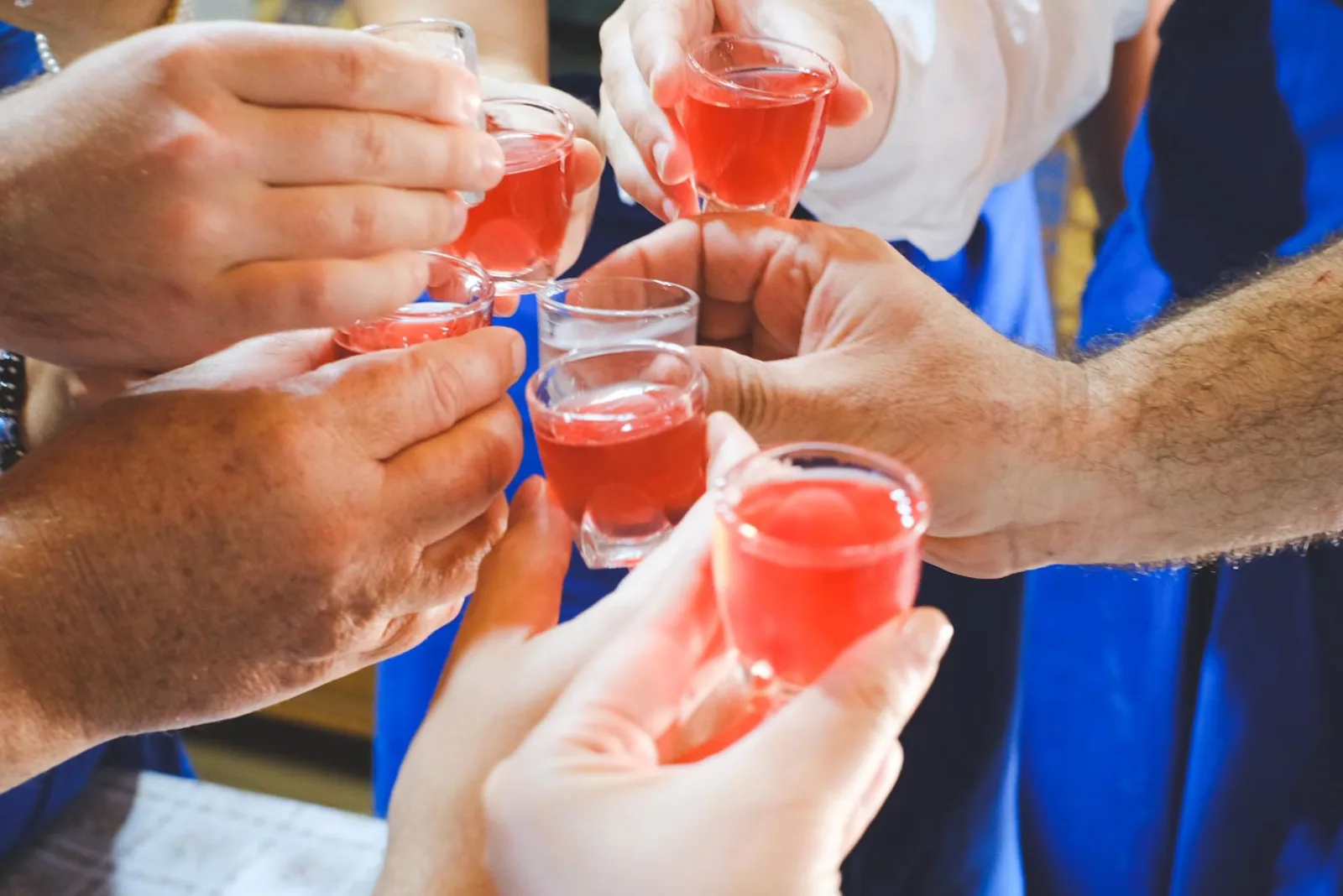 Guests raising small glasses of rose-tinted raki in a toast around a table