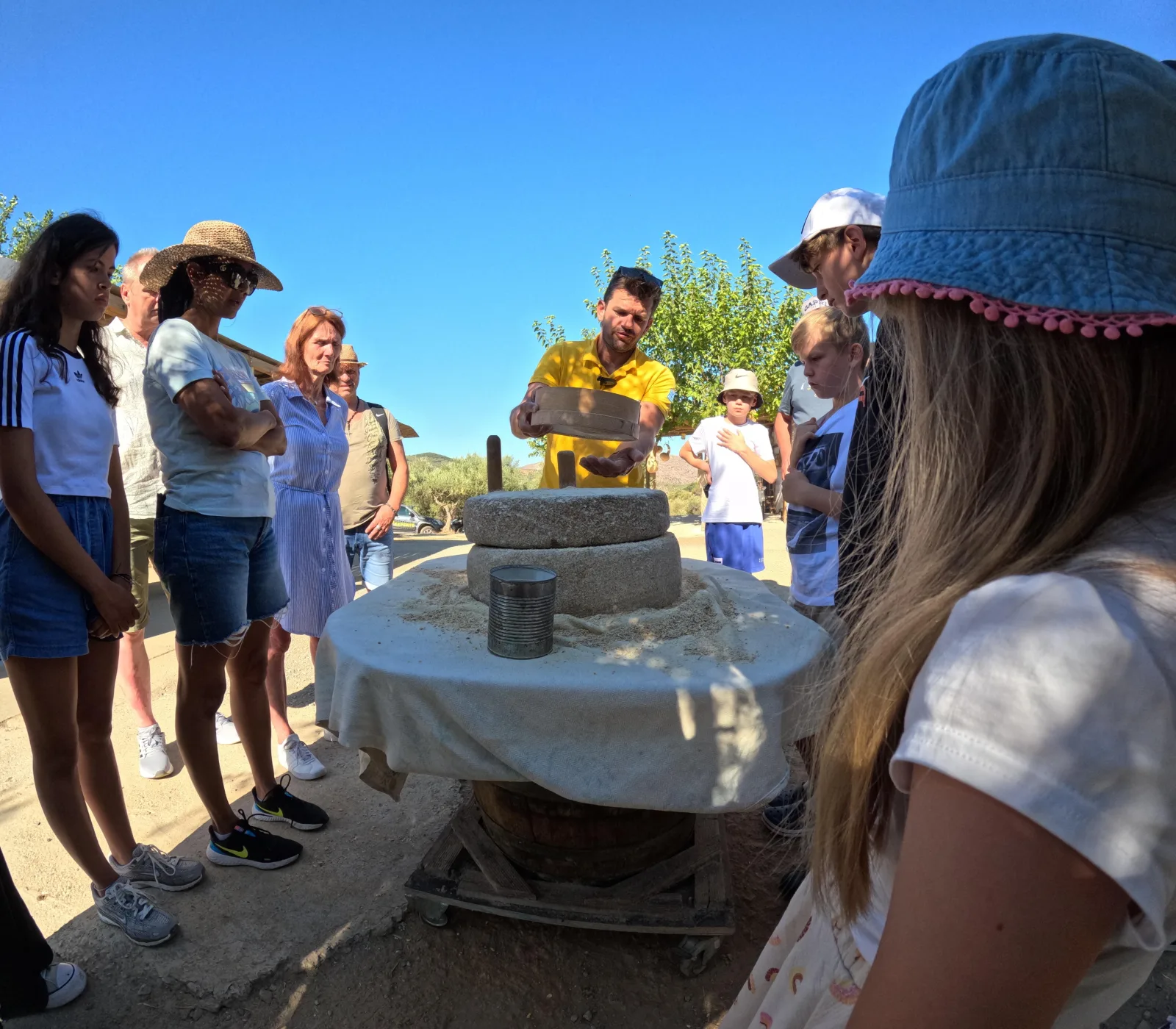 Guests gathered around a traditional stone olive press while the guide explains how it worked