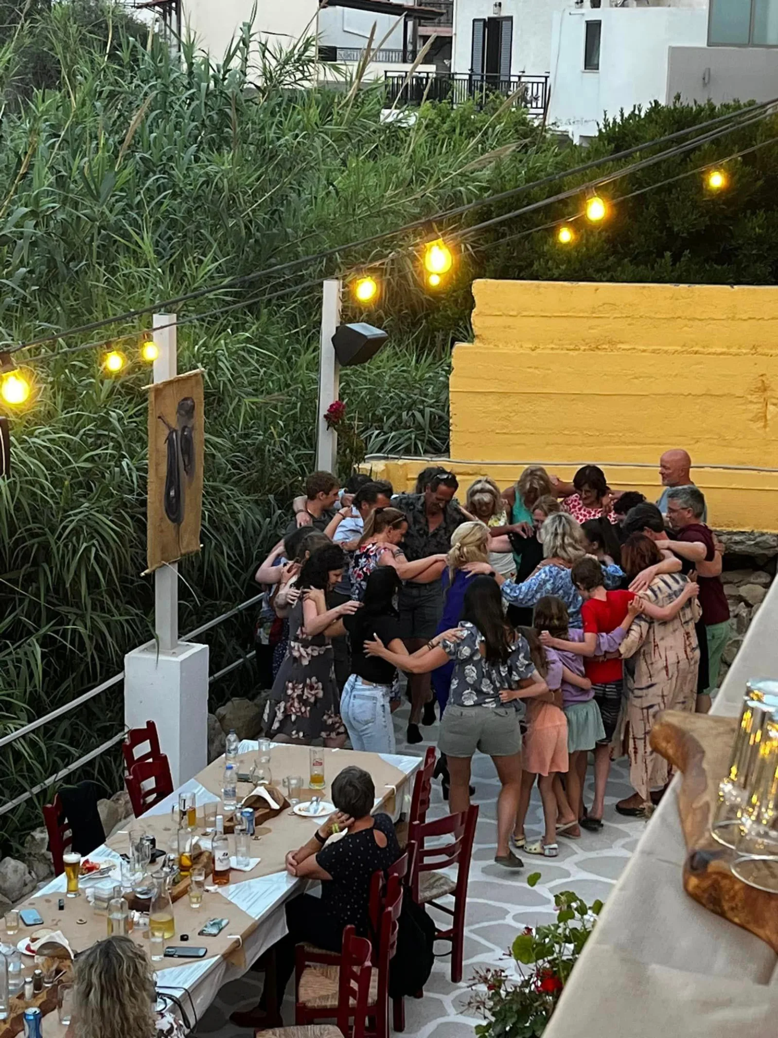 Guests dancing between the tables under festoon lights during the Greek night