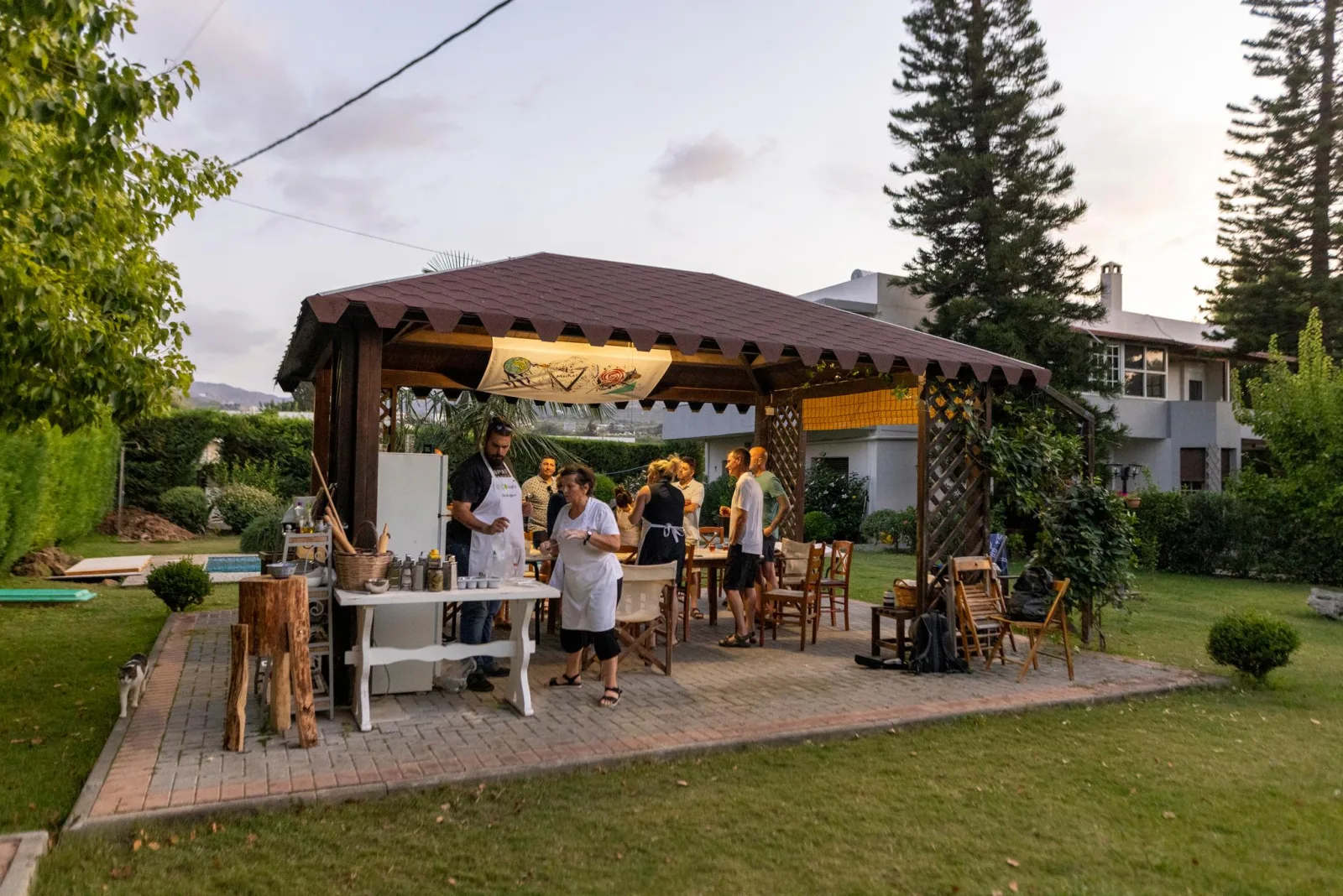 The garden pavilion at Pigi with guests gathered at the counter, lawn and trees behind