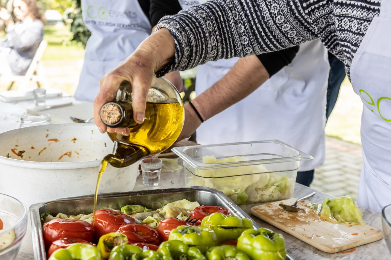 Olive oil being poured generously over a tray of stuffed peppers before baking