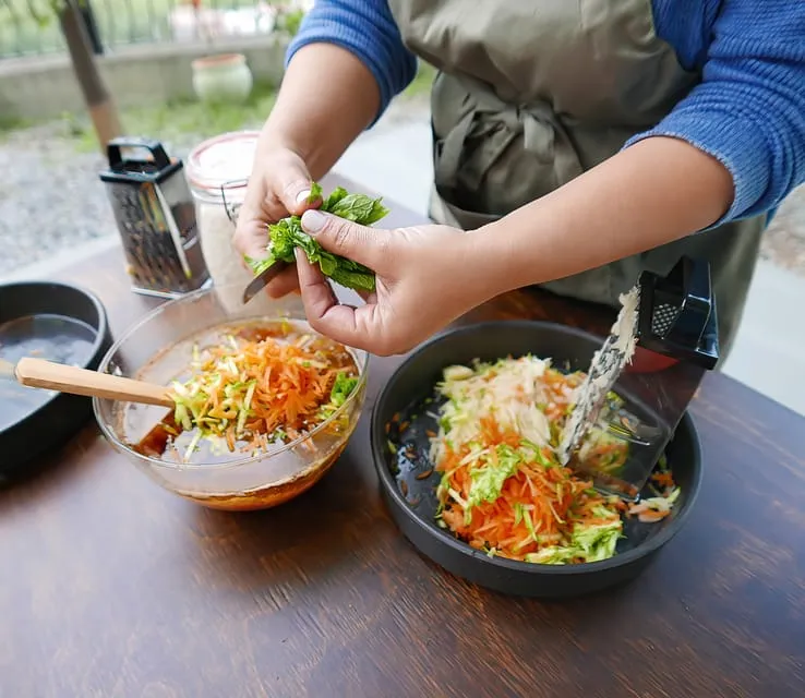 Grating courgette and carrot into a bowl, with fresh mint ready to add