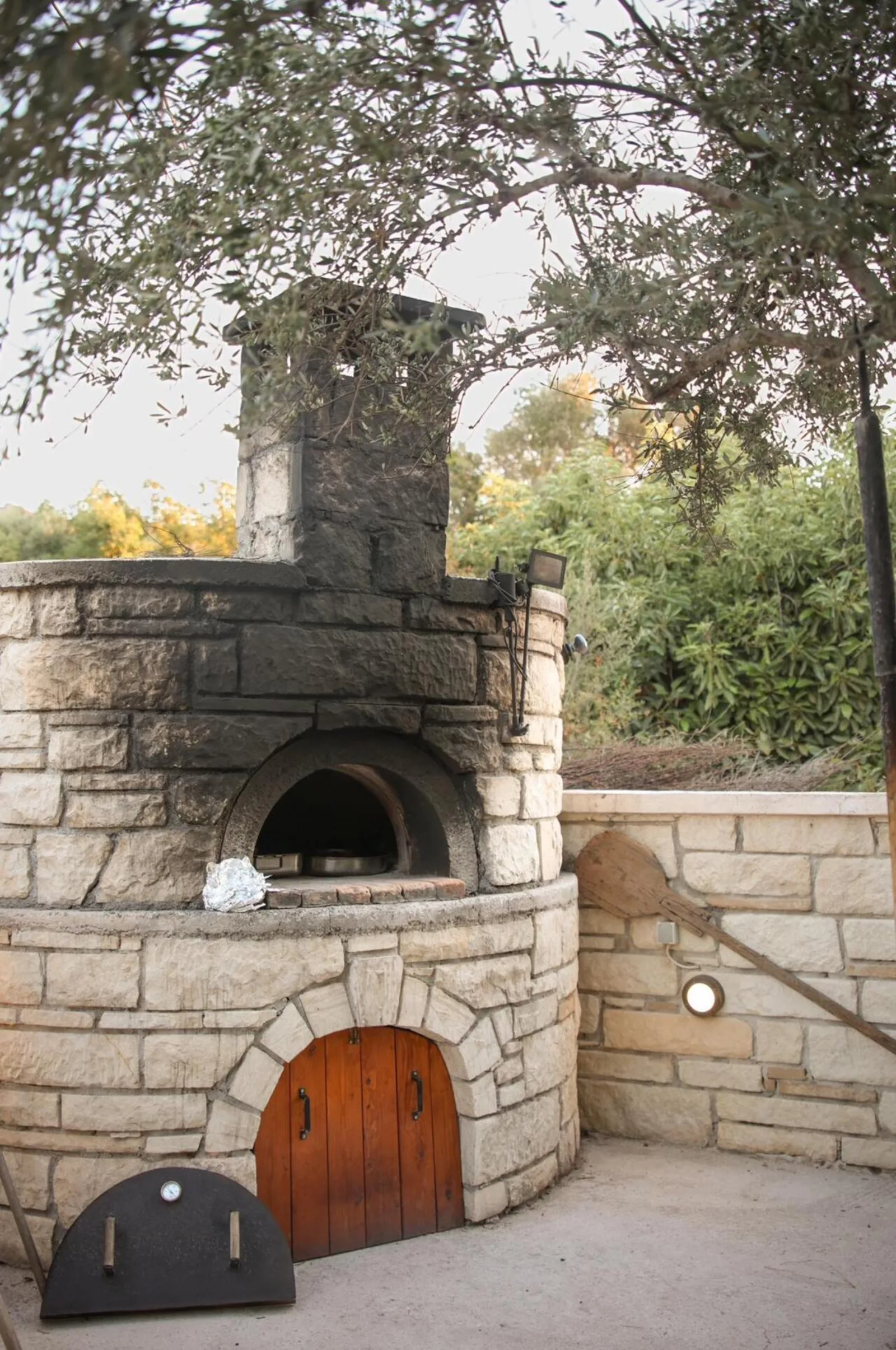 A stone wood-fired oven with an arched iron door standing in the garden at Nerokourou