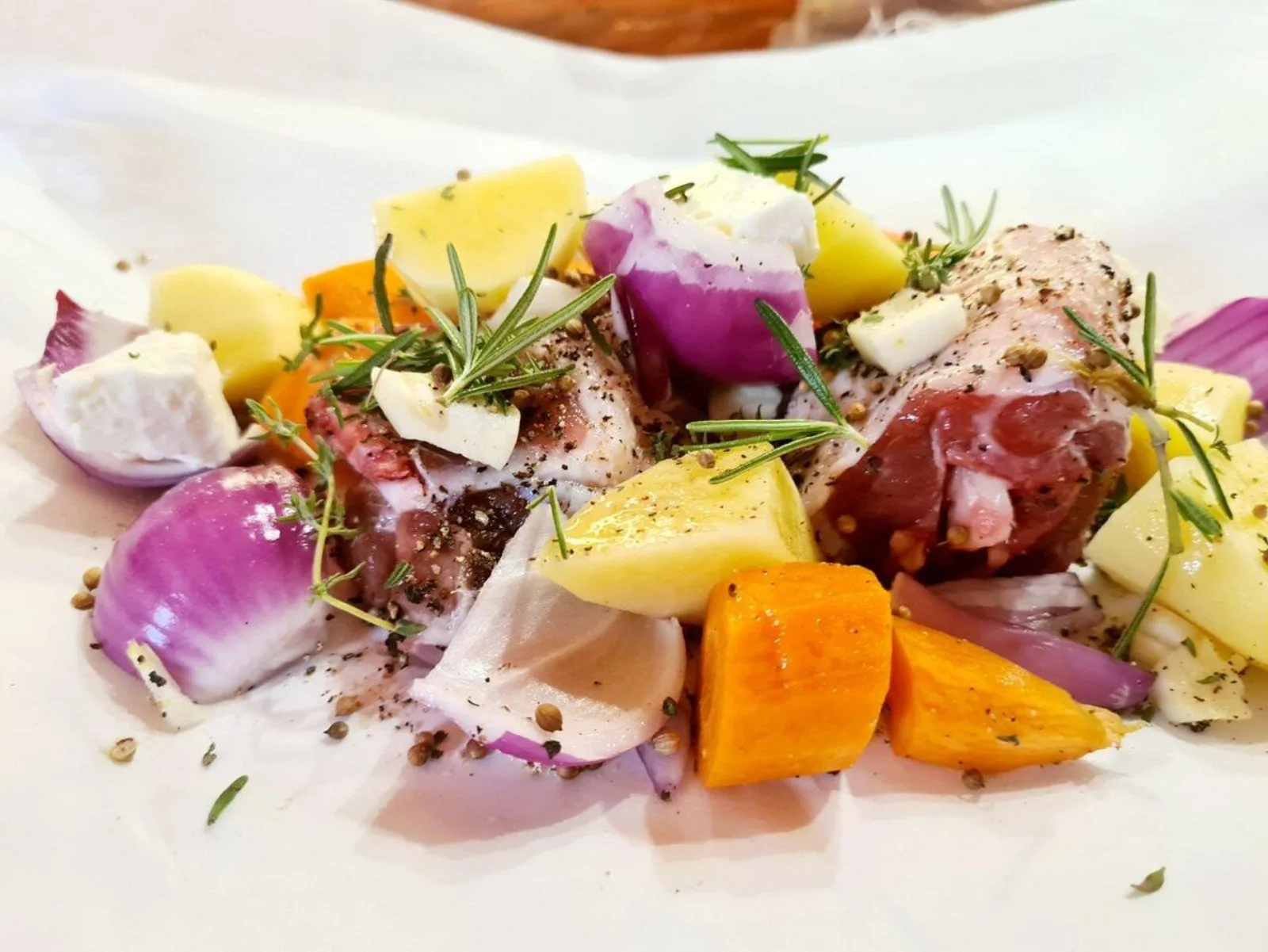 A platter of roasted vegetables with feta, red onion and rosemary