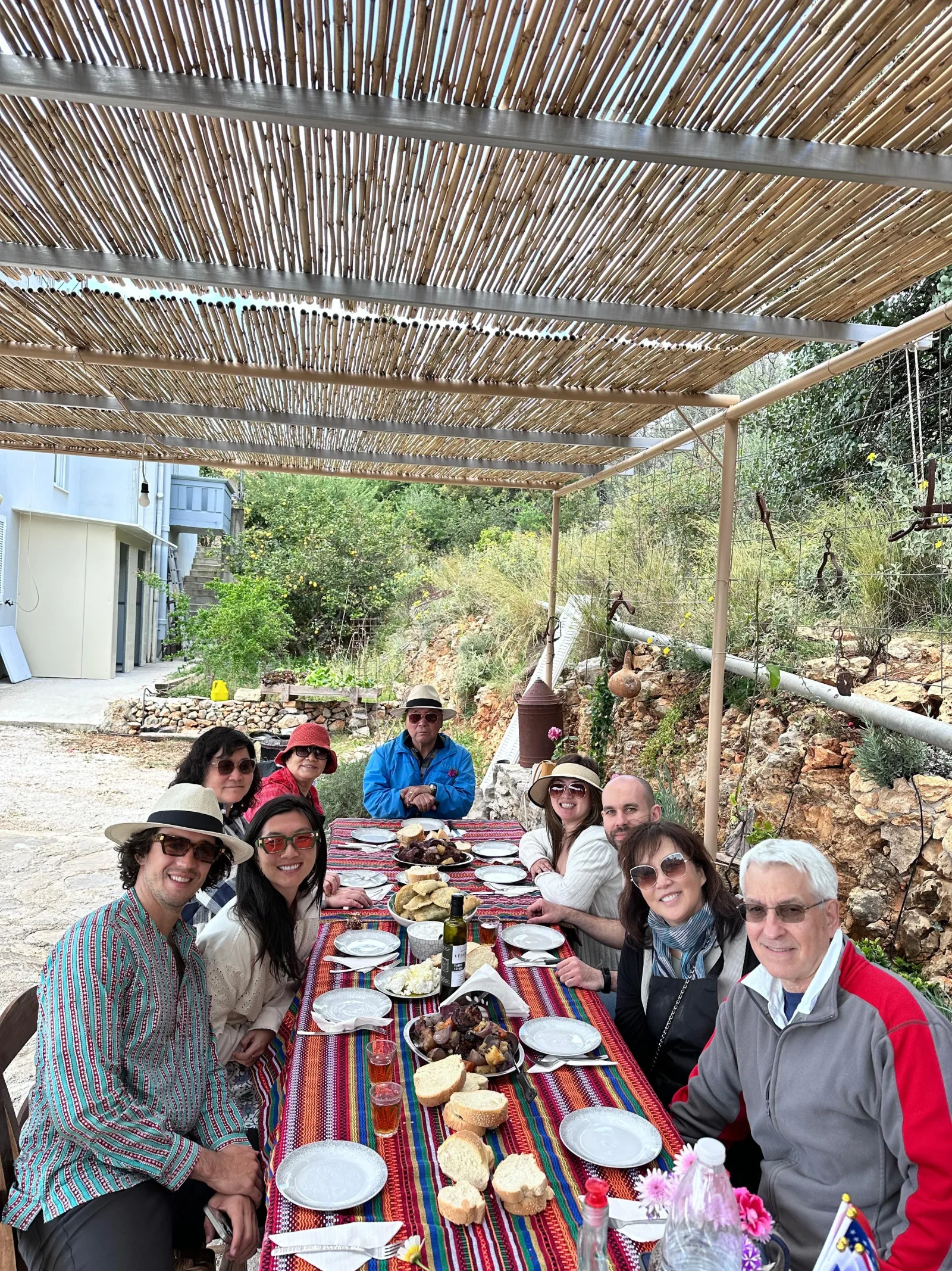 Guests eating together at a long table under a reed pergola on the farm