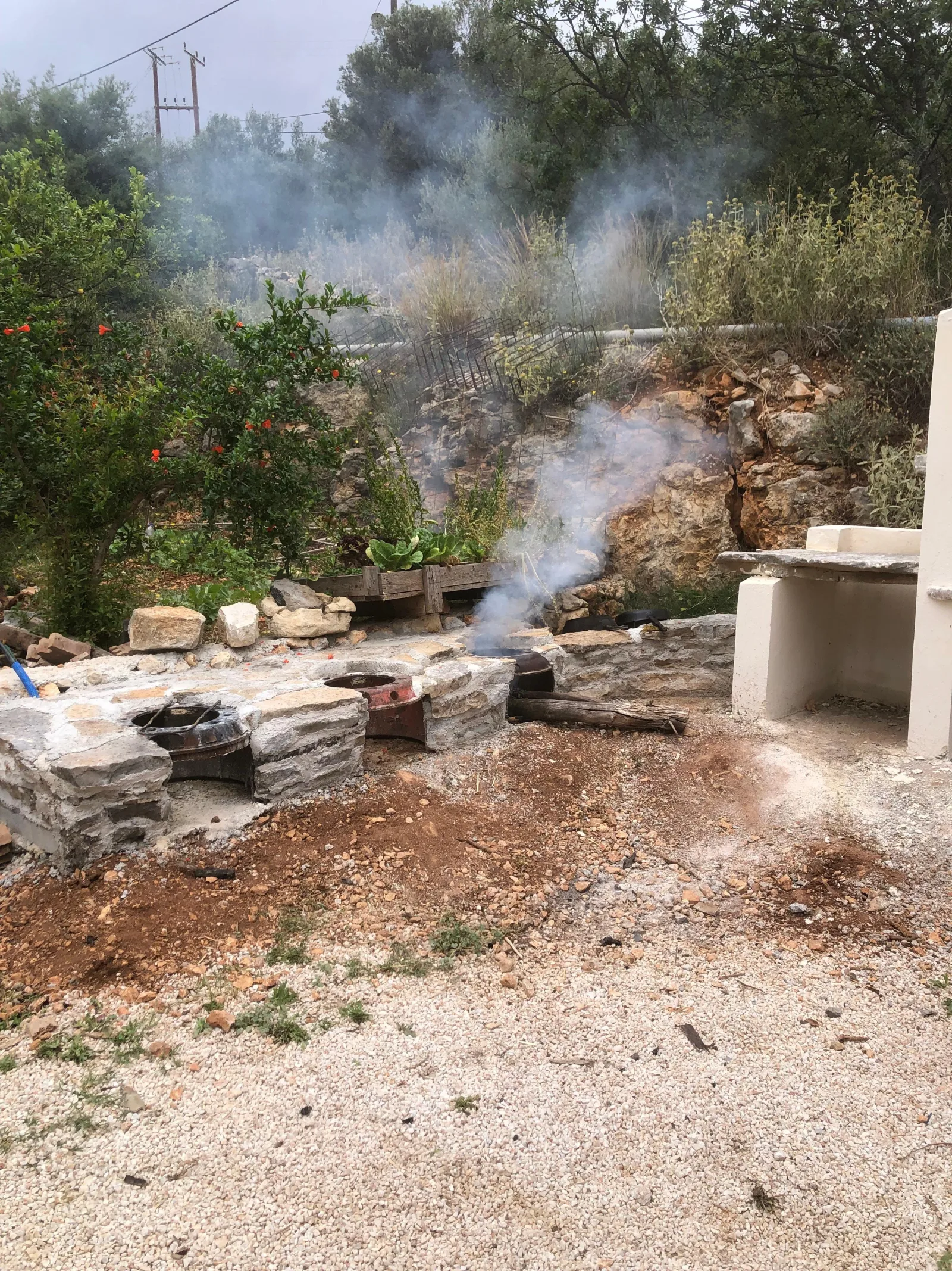 An open wood fire smoking beside the stone hearth in the farmyard, where all the cooking is done